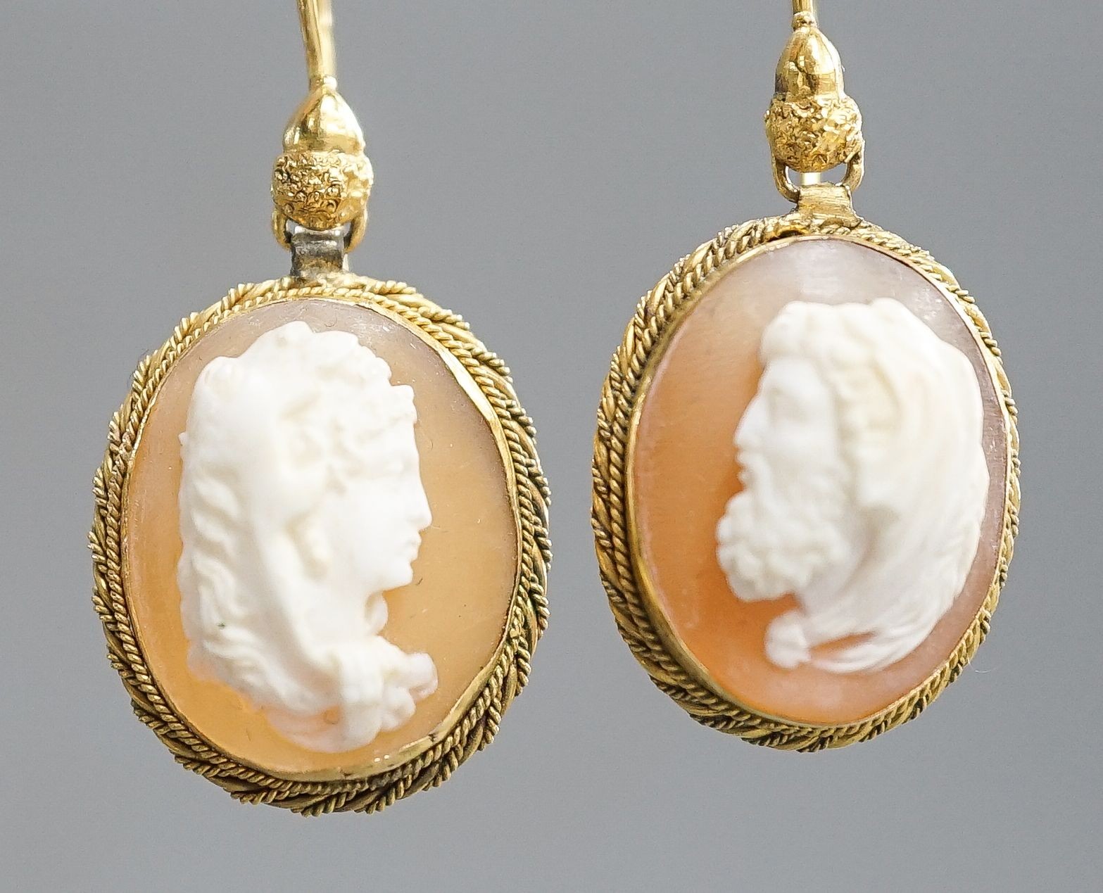 A pair of early 20th century yellow metal and oval cameo shell earrings, carved with a lady to sinister and a gentleman to dexter, overall 40mm, gross 6.2 grams.